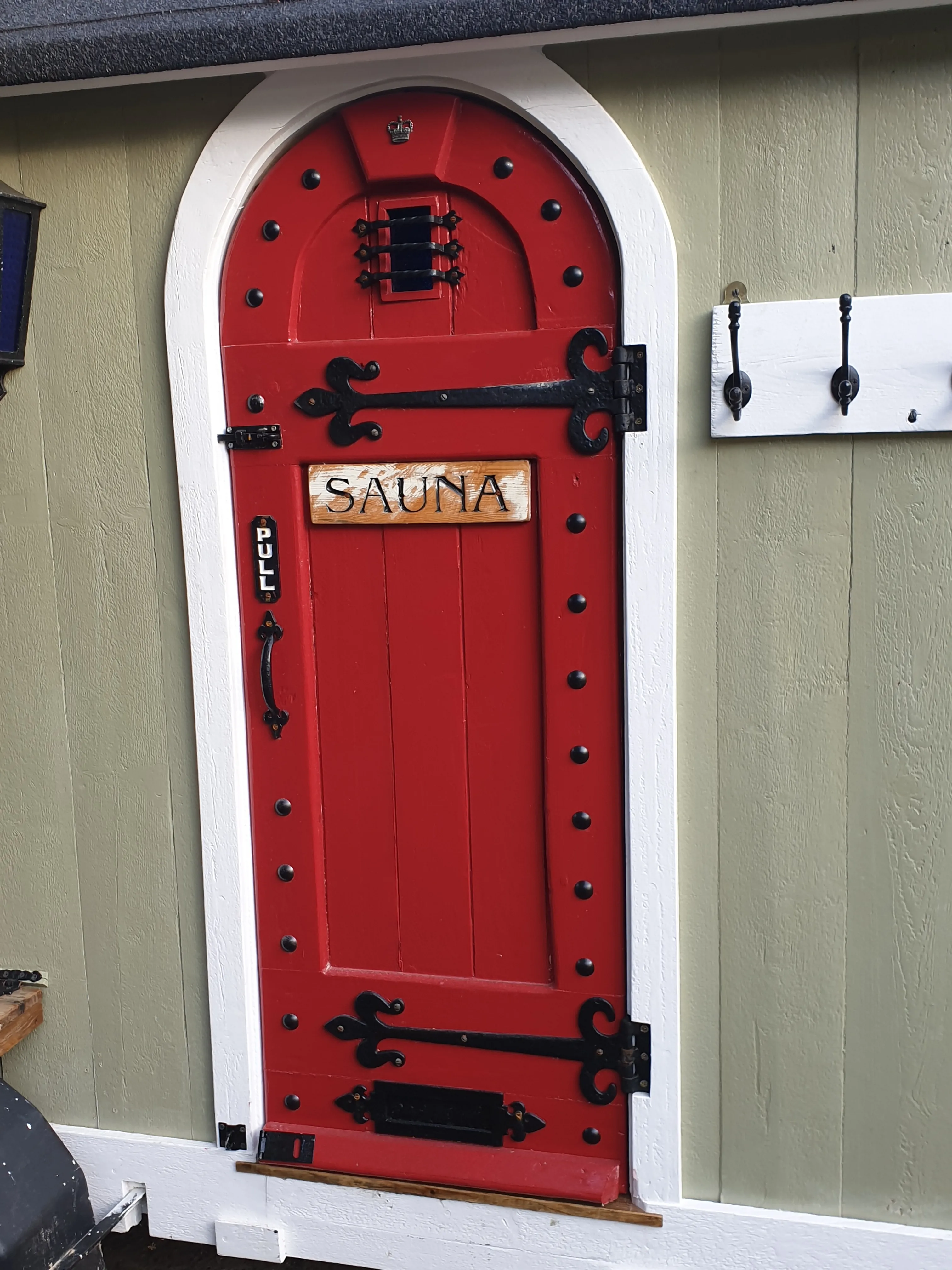 The pillar-box red arched door with black wrought-iron hinges